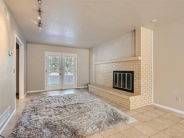 3540 E 5th Ave, Denver, CO 80206 - unfurnished living room featuring tile patterned floors, french doors, a fireplace, a textured ceiling, and track lighting