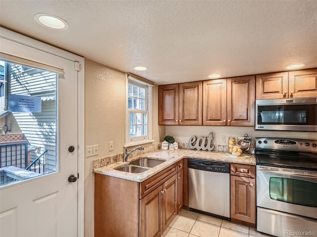 3540 E 5th Ave, Denver, CO 80206 - kitchen featuring appliances with stainless steel finishes, a sink, light stone countertops, plenty of natural light, and a textured ceiling