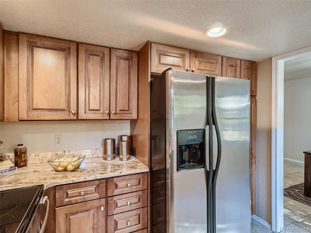 3540 E 5th Ave, Denver, CO 80206 - kitchen featuring stainless steel fridge, a textured ceiling, tile patterned flooring, brown cabinets, and light stone countertops