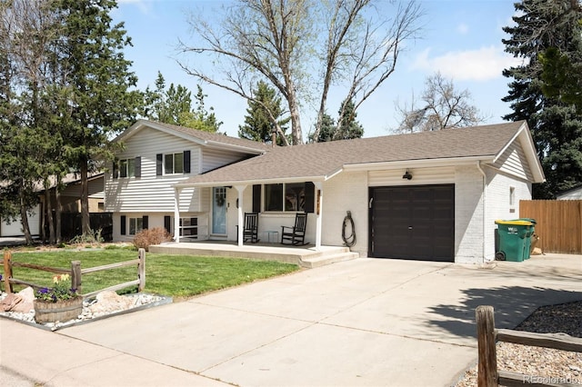 tri-level home featuring fence, an attached garage, a porch, a front yard, and concrete driveway