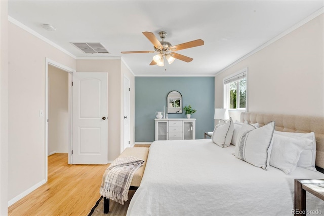bedroom with visible vents, a ceiling fan, light wood-style floors, and crown molding