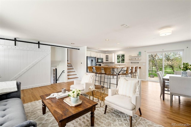 living room with baseboards, stairway, recessed lighting, a barn door, and light wood-style flooring
