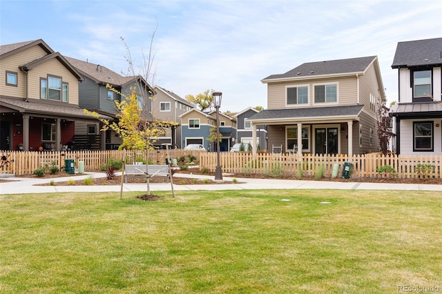 view of front of property featuring a front lawn, a residential view, covered porch, and a fenced front yard