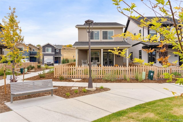 view of front of home with a fenced front yard, a residential view, and covered porch
