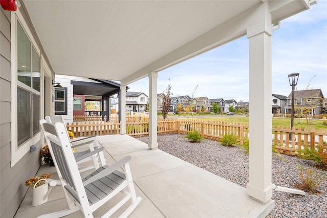 view of patio featuring a residential view, a porch, and fence