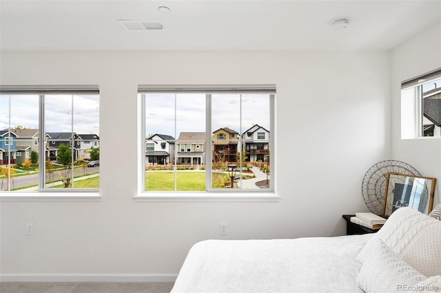bedroom with carpet, visible vents, a residential view, and baseboards