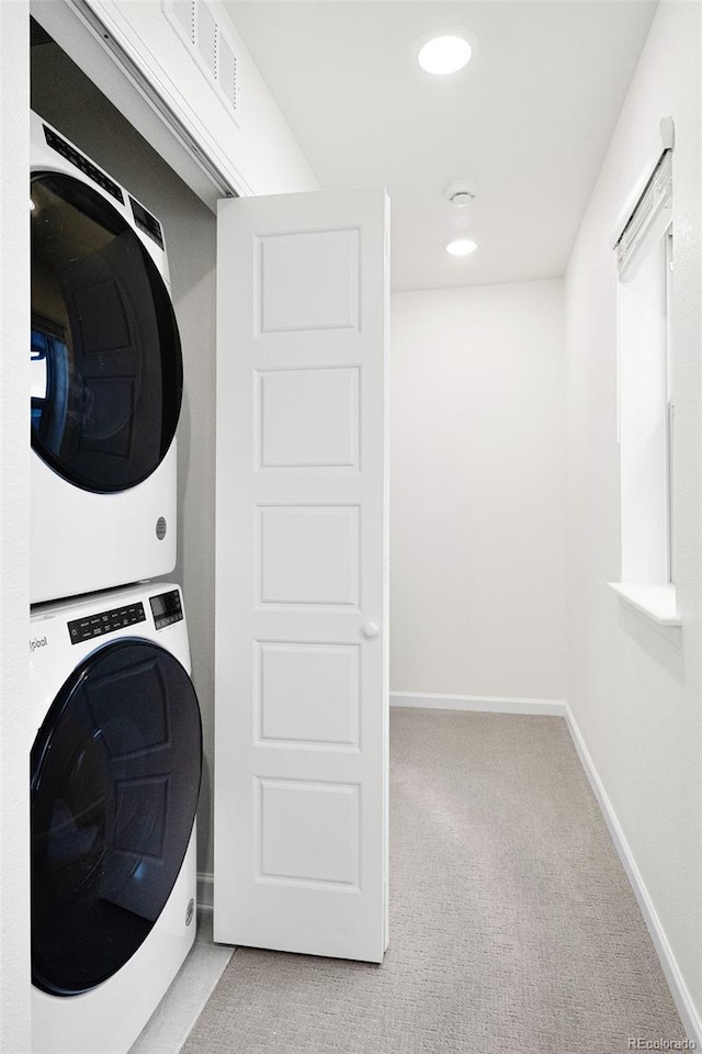 clothes washing area with stacked washer / dryer, light carpet, laundry area, baseboards, and visible vents