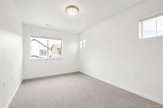 carpeted spare room featuring baseboards and visible vents
