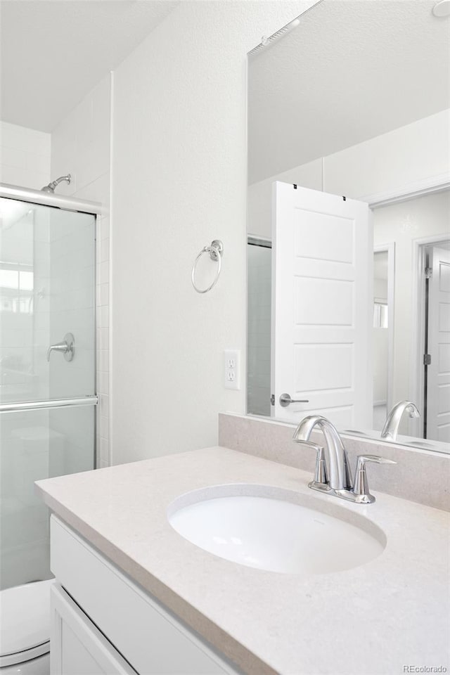 full bath with vanity, toilet, and a stall shower