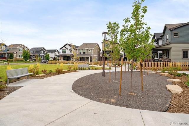 view of community featuring a yard, a residential view, and fence