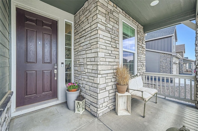 view of exterior entry with covered porch and stone siding
