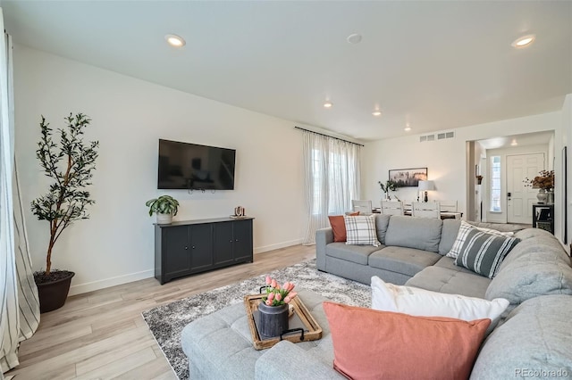 living room with light wood finished floors, baseboards, and recessed lighting