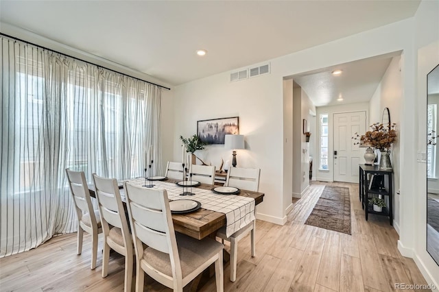 dining area featuring light wood-type flooring, a healthy amount of sunlight, and visible vents