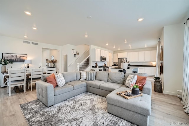 living room featuring light wood finished floors, stairs, visible vents, and recessed lighting