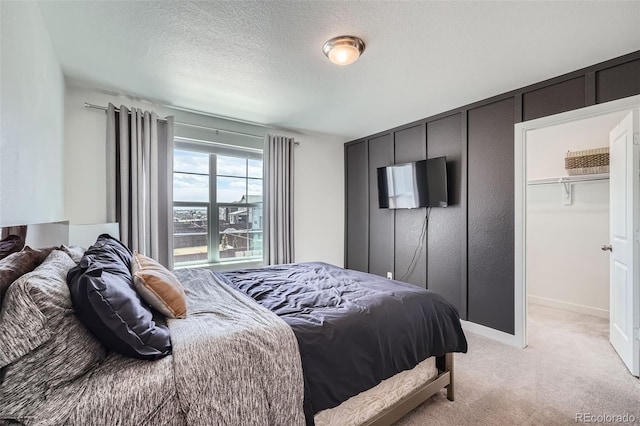bedroom with baseboards, a textured ceiling, and light colored carpet