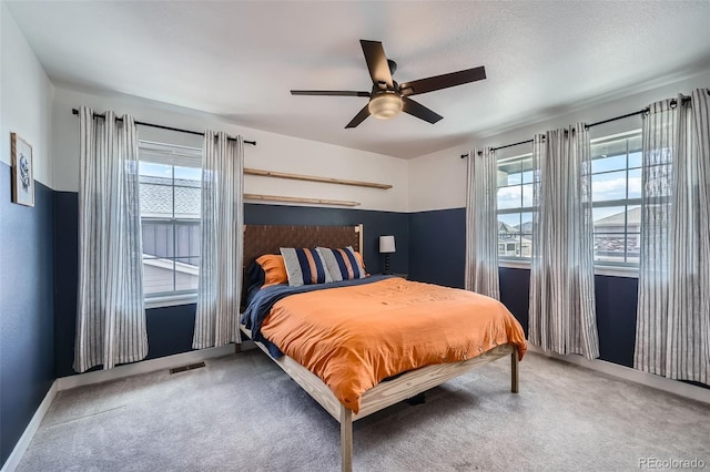 bedroom with carpet flooring, a ceiling fan, visible vents, and multiple windows