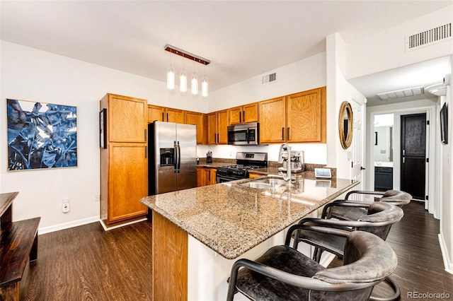 5439 S Dover St Unit 101, Littleton, CO 80123 - kitchen featuring stainless steel appliances, a peninsula, brown cabinets, and dark wood-type flooring