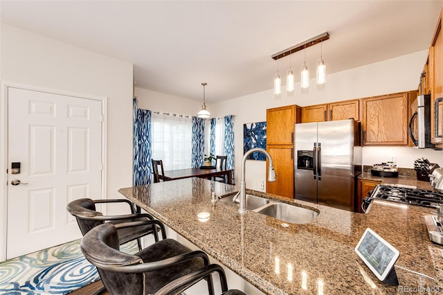 5439 S Dover St Unit 101, Littleton, CO 80123 - kitchen with stainless steel appliances, brown cabinets, a peninsula, a kitchen breakfast bar, and decorative light fixtures