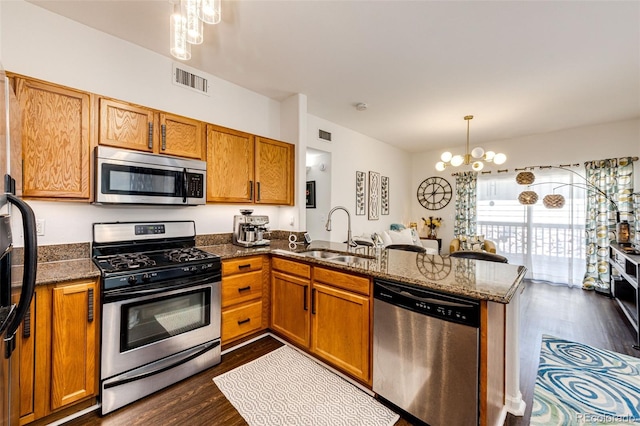 5439 S Dover St Unit 101, Littleton, CO 80123 - kitchen featuring appliances with stainless steel finishes, a chandelier, dark wood-type flooring, brown cabinetry, and a peninsula