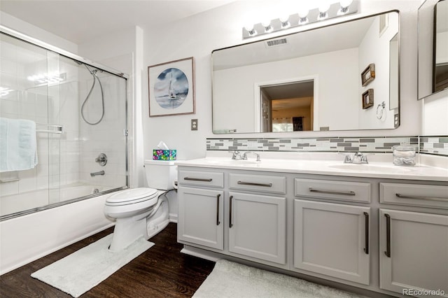 5439 S Dover St Unit 101, Littleton, CO 80123 - full bath with double vanity, wood finished floors, shower / bath combination with glass door, and decorative backsplash