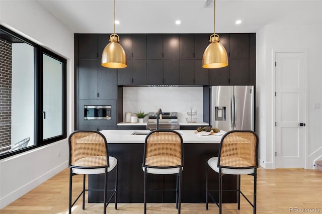 1250 Yates St, Denver, CO 80204 - kitchen featuring stainless steel appliances, light countertops, light wood-type flooring, a kitchen breakfast bar, and recessed lighting