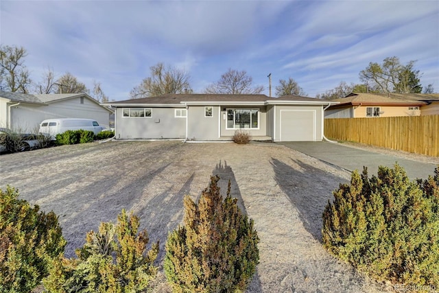 ranch-style home featuring concrete driveway, stucco siding, fence, and an attached garage