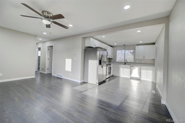 unfurnished living room featuring visible vents, baseboards, a sink, a ceiling fan, and dark wood finished floors