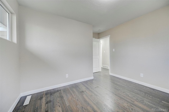 empty room with visible vents, baseboards, and wood finished floors