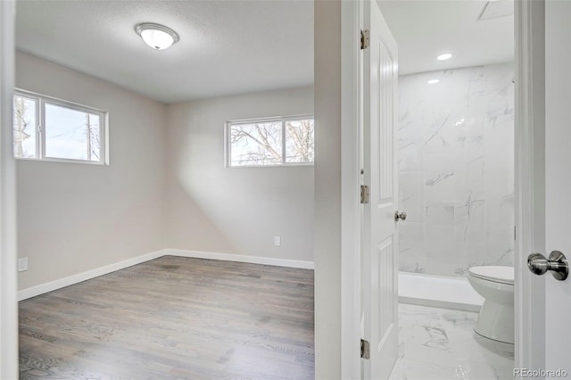 bathroom with toilet, a stall shower, baseboards, and a wealth of natural light