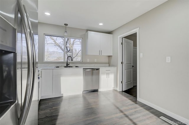 kitchen featuring white cabinets, a sink, light countertops, appliances with stainless steel finishes, and wood finished floors