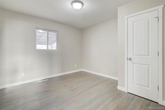 empty room with baseboards, wood finished floors, and a textured ceiling