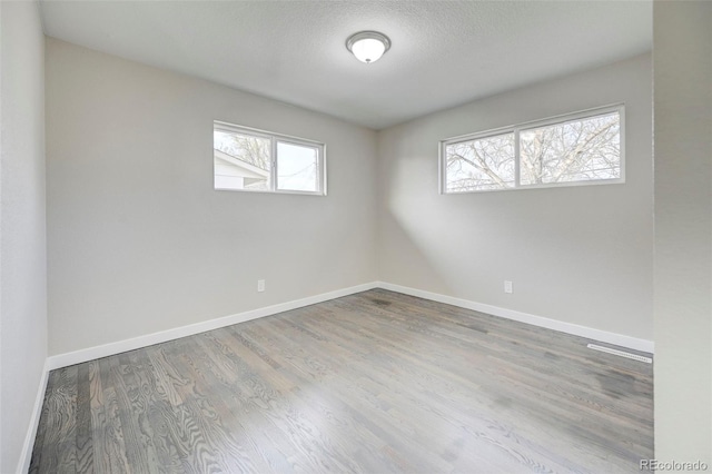 unfurnished room with baseboards, a textured ceiling, and wood finished floors