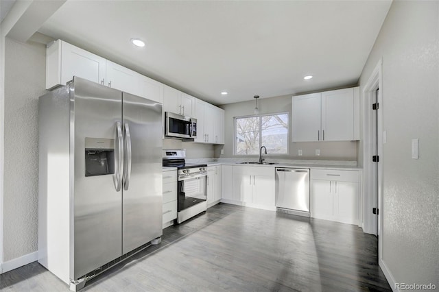 kitchen featuring white cabinets, a sink, light countertops, appliances with stainless steel finishes, and light wood finished floors