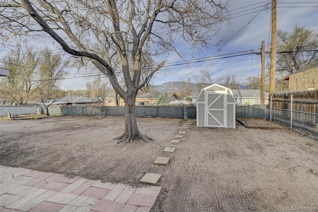 view of yard featuring a storage shed, a fenced backyard, and an outdoor structure