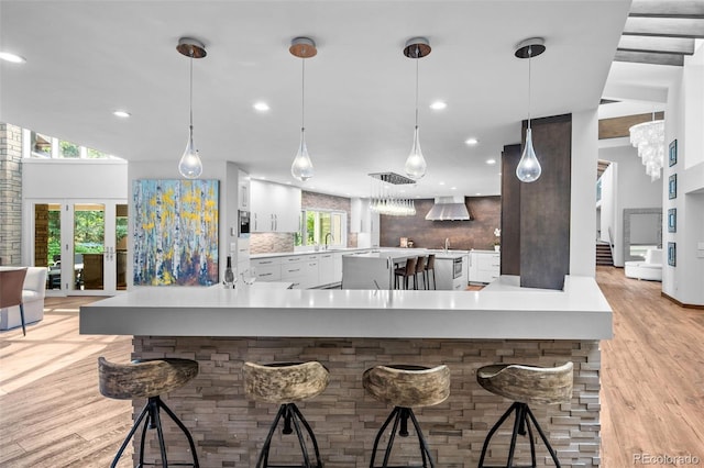 4766 S Fillmore Ct, Cherry Hills Village, CO 80113 - kitchen with wall chimney exhaust hood, healthy amount of natural light, light wood finished floors, white cabinets, and recessed lighting