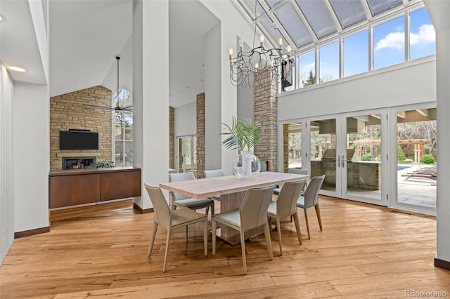 4766 S Fillmore Ct, Cherry Hills Village, CO 80113 - dining space with high vaulted ceiling, a chandelier, french doors, a fireplace, and hardwood / wood-style floors
