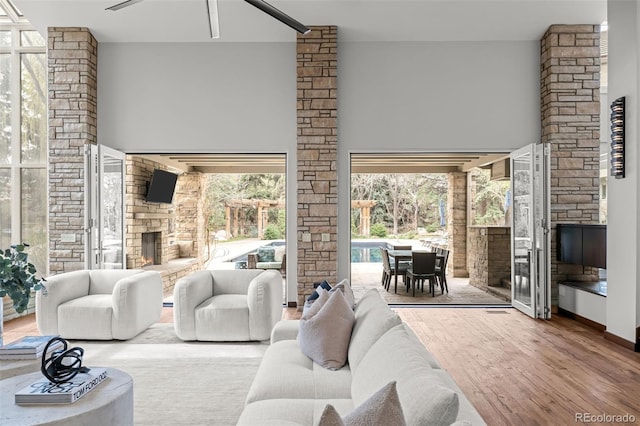 4766 S Fillmore Ct, Cherry Hills Village, CO 80113 - living area featuring a stone fireplace, wood finished floors, healthy amount of natural light, a ceiling fan, and a towering ceiling