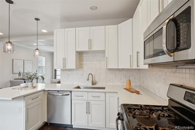 kitchen with white cabinetry, kitchen peninsula, stainless steel appliances, decorative light fixtures, and sink