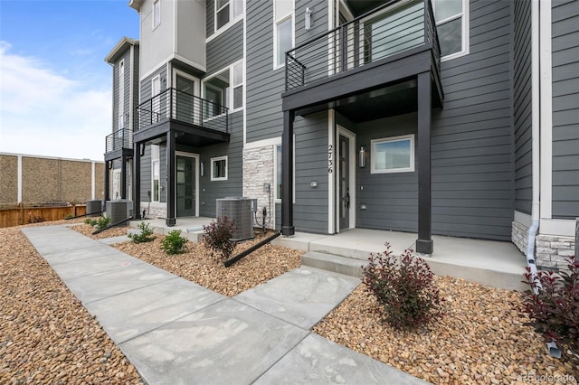 2736 W 68th Ave, Denver, CO 80221 - view of exterior entry with central AC, a balcony, and stone siding