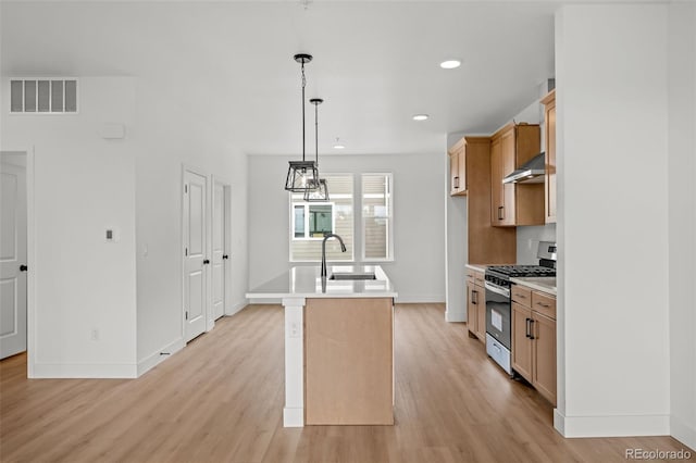 2736 W 68th Ave, Denver, CO 80221 - kitchen with stainless steel range with gas stovetop, a sink, wall chimney range hood, light wood finished floors, and baseboards