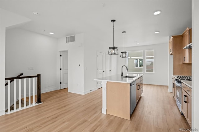 2736 W 68th Ave, Denver, CO 80221 - kitchen with appliances with stainless steel finishes, a sink, light wood-type flooring, light countertops, and an island with sink