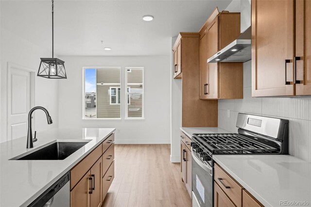 2736 W 68th Ave, Denver, CO 80221 - kitchen featuring appliances with stainless steel finishes, a sink, wall chimney range hood, light wood finished floors, and light countertops