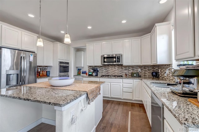 kitchen featuring stainless steel appliances, a sink, a center island, wood finished floors, and white cabinetry