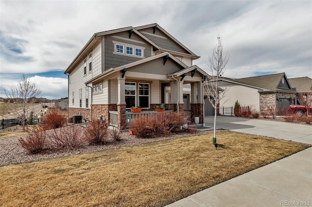 craftsman house featuring a porch, stone siding, central AC, concrete driveway, and a front yard