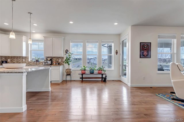 kitchen featuring backsplash, white cabinetry, light wood-type flooring, decorative light fixtures, and recessed lighting