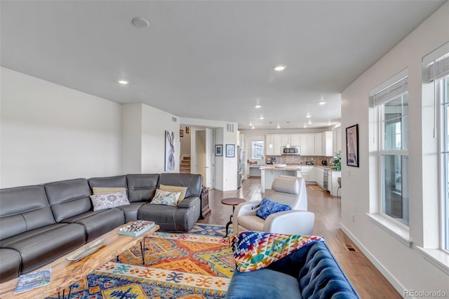 living area featuring light wood-style floors, recessed lighting, stairway, and baseboards