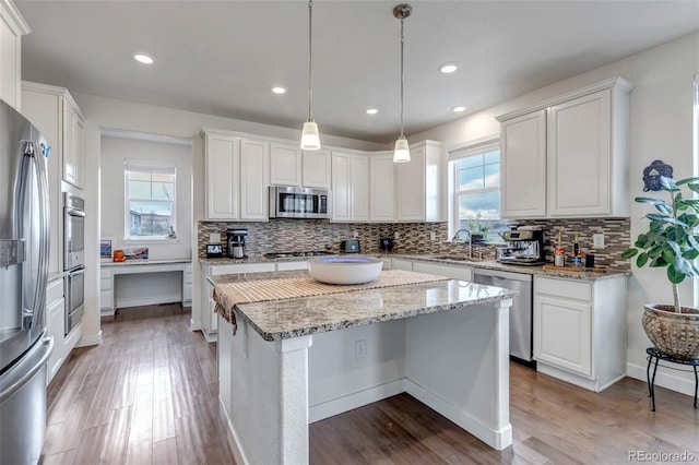 kitchen with appliances with stainless steel finishes, wood finished floors, decorative backsplash, and recessed lighting