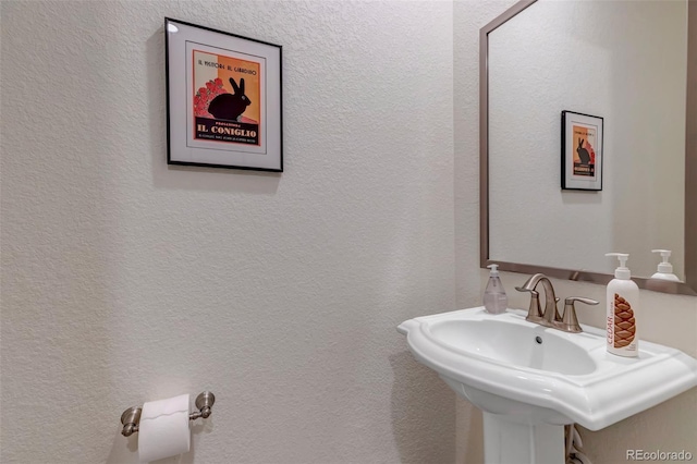 bathroom featuring a sink and a textured wall