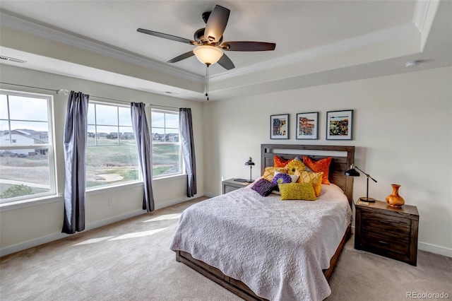 bedroom with a raised ceiling, light colored carpet, crown molding, baseboards, and a ceiling fan