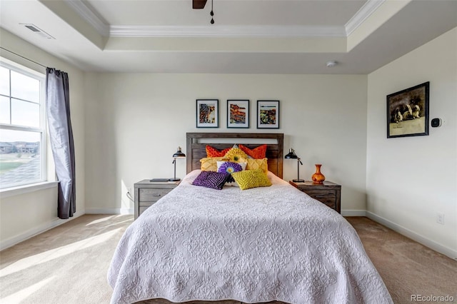 bedroom featuring a tray ceiling, ornamental molding, light colored carpet, baseboards, and ceiling fan